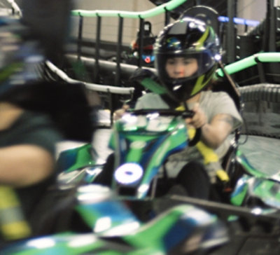  Child riding a go-kart in full helmet gear or an indoor track.