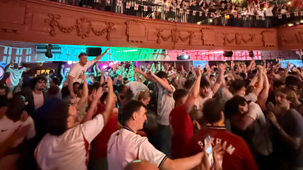 England fans, in red and white shirts, celebrate with their arms in the air in Manchester