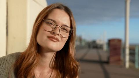 A woman wearing glasses sat on a bench. 