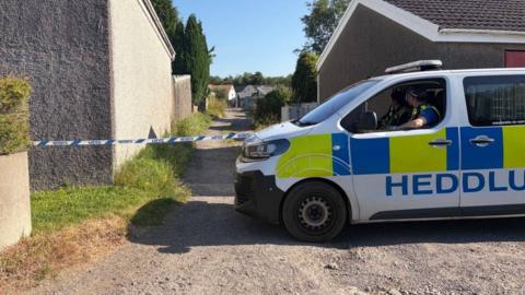 A police van is seen in front of police tape