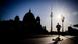 A runner in front of the Berlin Cathedral and TV tower, with the sun bright in the sky A runner in front of the Berlin Cathedral and TV tower, with the sun bright in the sky