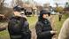 Two Ukrainian journalists record interviews while wearing protective gear.