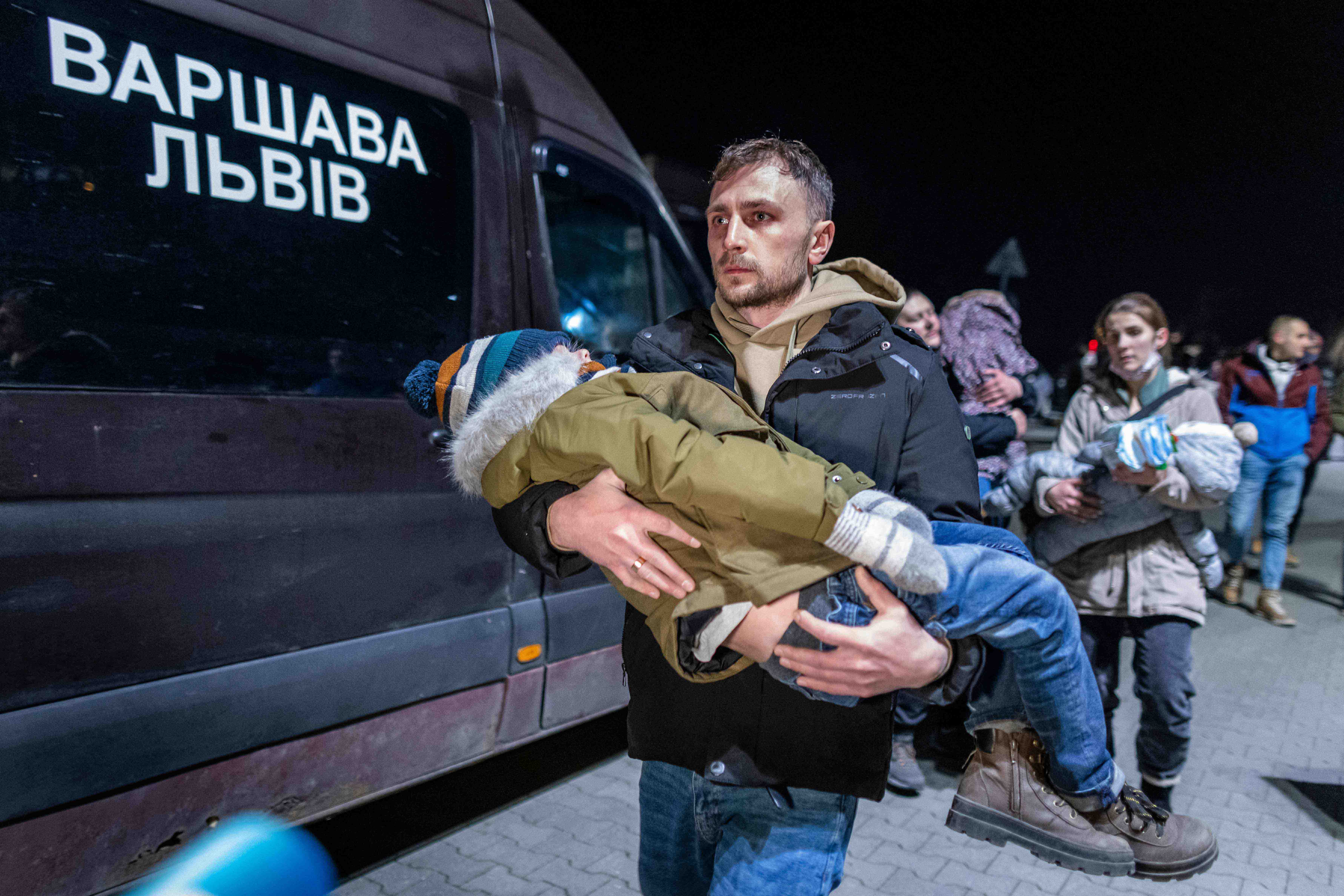 A volunteer carries a Ukranian child as civilians fleeing the conflict in Ukraine,&nbsp;arrive on buses in Przemsyl, eastern Poland, from the Medyka pedestrian border crossing.