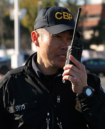 Man in CBP hat talking in to a radio