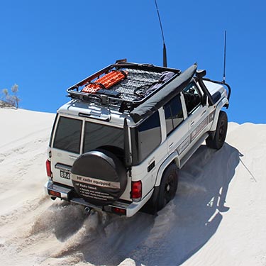 4x4 with large antennas driving up a sand dune