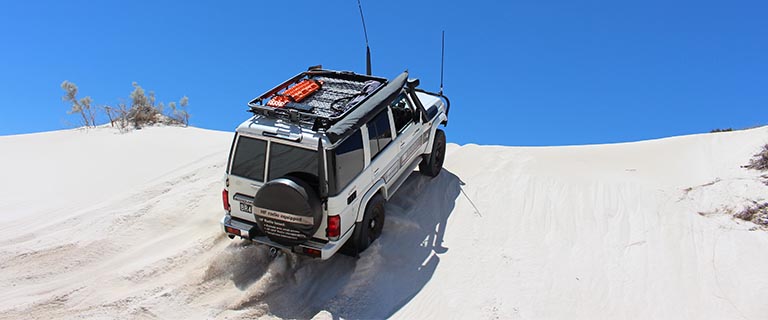 4x4 with large antennas driving up a sand dune